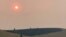 Smoke obscures the air and dims the sun over a hillside burned by a recent wildfire, in Missoula, Mont., on Sunday, July 18, 2021. Extreme heat descended on parts of the U.S. northern Rocky Mountains on Monday, July 19 as authorities struggled to…