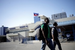 Workers with the Haiti's Ministry of Public Health and Population walk outside of International Airport Toussaint Louverture, in Port-au-Prince, Haiti, March 15, 2020.