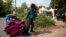FILE - A pregnant mother who said she was from Haiti and her daughter are watched by Royal Canadian Mounted Police officers as they prepare to cross the U.S.-Canada border into Hemmingford, Quebec, from Champlain, N.Y.