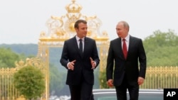 President Emmanuel Macron, left, and his Russian counterpart Vladimir Putin walk, as they meet for talks before the opening of an exhibition marking 300 years of diplomatic ties between the two countries at Palace of Versailles, May 29, 2017. 