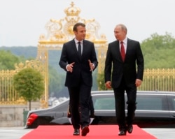 FILE - President Emmanuel Macron and his Russian counterpart Vladimir Putin walk, as they meet for talks before the opening of an exhibition marking 300 years of diplomatic ties between the two countries at Palace of Versailles, May 29, 2017.