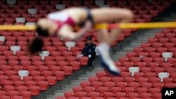 FILE - A security guard watches as a Russia athlete, front, makes an attempt at the women's high jump during the 2014 IAAF World Challenge Beijing held at China's National Stadium in Beijing, Wednesday, May 21, 2014. 