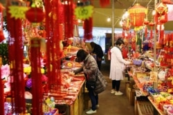FILE - People wearing masks to protect against the coronavirus shop for the Lunar New Year holiday, in Taipei, Taiwan, Feb. 9, 2021. Taiwanese returning home to shelter from the pandemic have provided an unexpected boost for the island's economy.