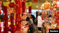 FILE - People wearing masks to protect against the coronavirus shop ahead of the Lunar New Year holiday, in Taipei, Taiwan, Feb. 9, 2021. Taiwanese returning home to shelter from the pandemic have provided an unexpected boost for the island's economy. 