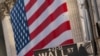FILE - A Wall Street sign is seen against the background of a giant American flag hanging on the building of the New York Stock Exchange, in New York City, Sept. 21, 2020.