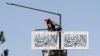 An Afghan worker hangs a Taliban flag along a street in Kabul on Aug. 13, 2023.