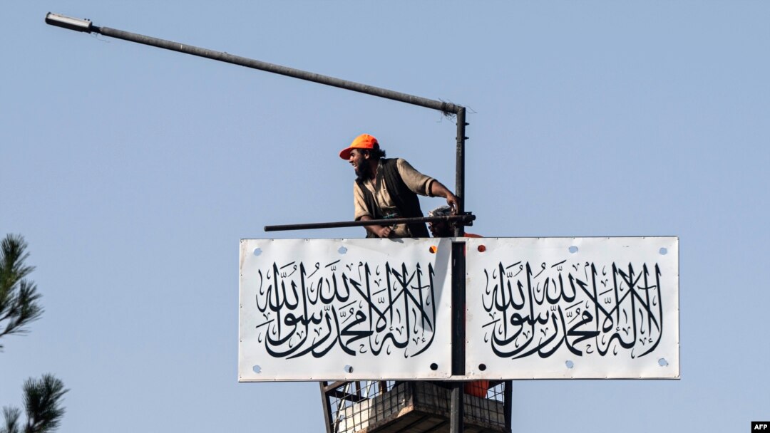 An Afghan worker hangs a Taliban flag along a street in Kabul on Aug. 13, 2023.
