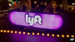 FILE - Lyft’s new Amp glows on the dashboard of a car in San Francisco, Feb. 9, 2017.