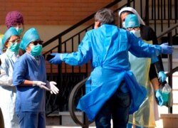 Medical personnel talk outside the retirement home Giovanni XIII, where coronavirus swabs were carried out on the staff of the facility, after the death of a patient, in Rome, March 24, 2020.