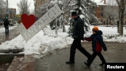 People walk in the center of the rebel-controlled city of Luhansk, Ukraine, Nov. 23, 2017. The sign reads, "I love Luhansk." 