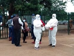 Zimbabwe's Movement for Democratic Change Alliance legislator, Joana Mamombe (left) and activist Cecilia Chimbiri (both in PPEs) arriving at Harare Magistrates Court on Feb. 02, 2021 in the company of police. (Columbus Mavhunga/VOA)