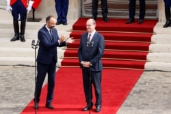 FILE - Former French Prime Minister Edouard Philippe applauds newly appointed Prime Minister Jean Castex in the courtyard of the Matignon Hotel during the handover ceremony in Paris, France, July 3, 2020.
