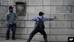 Un manifestante apunta con una honda a la policía durante una protesta de veteranos que exigen que se apruebe una ley que los compense por haber servido durante la guerra civil del país, frente al edificio del Congreso en la Ciudad de Guatemala, el martes 19 de octubre de 2021.