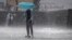 FILE - A girl with a scooter drives through a hailstorm in Munich, Germany, May 19, 2017.