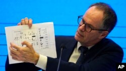 In this Feb. 9, 2021, file photo, Peter Ben Embarek of the World Health Organization team holds up a chart showing pathways of transmission of the virus during a joint news conference at the end of the WHO mission in Wuhan. (AP Photo/Ng Han Guan, File)