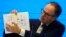 In this Feb. 9, 2021, file photo, Peter Ben Embarek of the World Health Organization team holds up a chart showing pathways of transmission of the virus during a joint news conference at the end of the WHO mission in Wuhan. (AP Photo/Ng Han Guan, File)