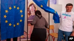 Una mujer entra en una cabina de votación para votar en el Parlamento Europeo y en las elecciones locales en Baleni, Rumania, el domingo 9 de junio de 2024. AP