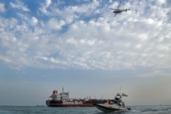 FILE - A speedboat and a helicopter of the Iran's Revolutionary Guard move around a British-flagged oil tanker Stena Impero, which was seized by the Guard, in the Iranian port of Bandar Abbas, July 21, 2019.