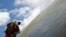 A man carrying prayer flags offered by the devotees, climbs to hang them on the Boudhanath Stupa, a UNESCO world heritage site famous among tourists, in Kathmandu, Nepal.