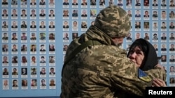 A Ukrainian serviceman hugs a woman as they visit the Wall of Remembrance to pay tribute to killed Ukrainian servicemen during a commemorative ceremony to mark the Volunteer Day honoring fighters, who joined the Ukrainian armed forces, in Kyiv, Ukraine March 14, 2023.