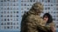 A Ukrainian serviceman hugs a woman as they visit the Wall of Remembrance to pay tribute to killed Ukrainian servicemen during a commemorative ceremony to mark the Volunteer Day honoring fighters, who joined the Ukrainian armed forces, in Kyiv, Ukraine March 14, 2023.