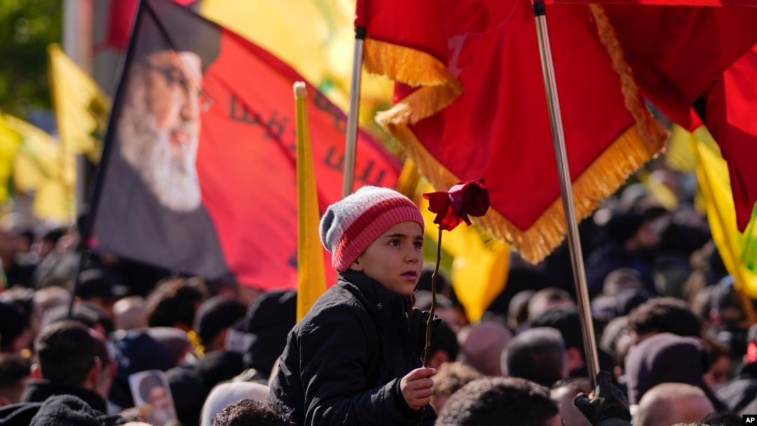 A boy holds a flower during the funeral procession of Hezbollah's former leader Hassan Nasrallah and his cousin and successor Hashem Safieddine, in Beirut, Feb. 23, 2025.