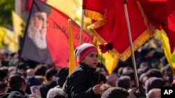 A boy holds a flower during the funeral procession of Hezbollah's former leader Hassan Nasrallah and his cousin and successor Hashem Safieddine, in Beirut, Feb. 23, 2025.