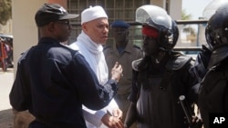 FILE - In this March 15, 2013 photo, Karim Wade, center, the son of former Senegalese President Abdoulaye Wade, is blocked by police as he tries to approach supporters outside the office of the special prosecutor investigating him on charges of embezzled funds, in Dakar, Senegal.