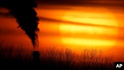 In this Monday, Feb. 1, 2021 file photo, emissions from a coal-fired power plant are silhouetted against the setting sun in Independence, Mo. A United Nations report released on Thursday, Feb. 18, 2021 says humans are making Earth a broken and increasingly unlivable planet throug