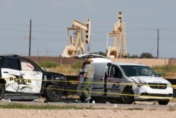 FILE - Law enforcement officials process the crime scene, Sept. 1, 2019, in Odessa, Texas, from a shooting that ended with the alleged attacker being shot dead by police in a stolen mail van, right.