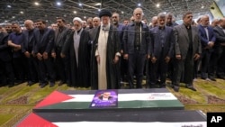 Udhëheqësi suprem i Iranit Ayatollah Ali Khamenei kryeson homazhet dhe lutjet para arkivoleve të udhëheqësit të Hamasit, Ismail Hanijeh dhe truprojës së tij në Teheran më 1 gusht, 2024/Zyra e udhëheqësit suprem të Iranit përmes AP