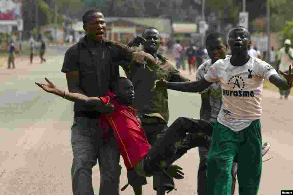 People carry a man who was injured by a tear gas canister shot by AU peacekeeping soldiers to disperse a crowd near Miskine, Bangui, Feb. 7, 2014.