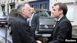 French President Emmanuel Macron (R) is welcomed by the archbishop of Marseille and president of the Bishops' Conference of France (CEF) Georges Pontier, upon his arrival at a meeting of the Bishops' Conference of France (CEF) at College des Bernardins in Paris, April 9, 2018. 