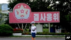 Seorang polisi lalu lintas Korea Utara berdiri di depan slogan propaganda: "Menjaga dengan sikap laksanakan-atau-mati di Pyongyang. (Foto:dok)