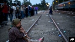 Une réfugiée afghane, tenant sa fille dans ses bras, se repose en attendant de monter dans un train en direction de la frontière autrichienne, à Roszke, dans le sud de la Hongrie, 14 septembre 2015 (AP Photo/Muhammed Muheisen)