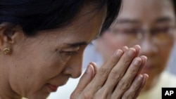 Burma's pro-democracy leader Aung San Suu Kyi gestures as she offers yellow robes to Buddhist monks in front of the National League for Democracy party's headquarters in Rangoon, Dec. 8, 2010.