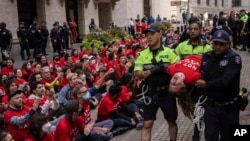 Police officers detain a demonstrator protesting Israel's war against Hamas as they occupy an area outside the New York Stock Exchange, in New York, Oct. 14, 2024