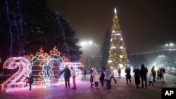 La gente camina en una plaza decorada para las festividades de Navidad y Año Nuevo en Donetsk, en la región de Donetsk controlada por Rusia, en el este de Ucrania, el 31 de diciembre de 2024.