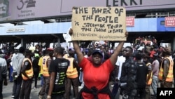 Une manifestante tient une pancarte pour protester contre les abus de la brigade spéciale anti-vol (SRAS) sur la place de péage de Lekki à Lagos, au Nigeria, le 12 octobre 2020.