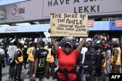 FILE - A demonstrator holds a placard to protest abuses by the Special Anti-Robbery Squad (SARS) at the Lekki toll Plaza in Lagos, Nigeria, Oct. 12, 2020.
