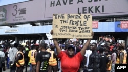 A demonstrator holds a placard to protest against abuses by the Special Anti-Robbery Squad (SARS) at the Lekki toll plaza in Lagos, Nigeria, Oct. 12, 2020.