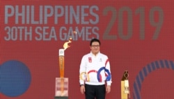 Philippines Southeast Asian Games Organizing Committee Chief Opening Officer Ramon Suzara poses with the Southeast Asian Games torch and lantern during the Flame Handover Ceremony for the 30th Southeast Asian Games in Kuala Lumpur, Malaysia.