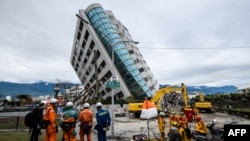 Para petugas SAR dari Jepang dan Taiwan memperhatikan gedung Yun Tsui yang miring akibat guncangan gempa di Kota Hualien, Taiwan, tahun lalu, 9 Februari 2018. 