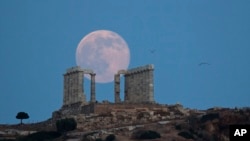 Bulan purnama terlihat di belakang kuil kuno Poseidon di Cape Sounion, Yunani. (Foto: Dok)