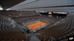 FILE - Rows of empty seats are seen at the Roland Garros stadium in Paris as Serbia's Novak Djokovic and Spain's Rafael Nadal warm up for the final match of the French Open tennis tournament, Oct. 11, 2020.