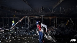 La gente saca elementos de una tienda incendiada el día después de las protestas contra el gobierno del presidente colombiano Iván Duque, en Cali, Colombia, el 29 de mayo de 2021.