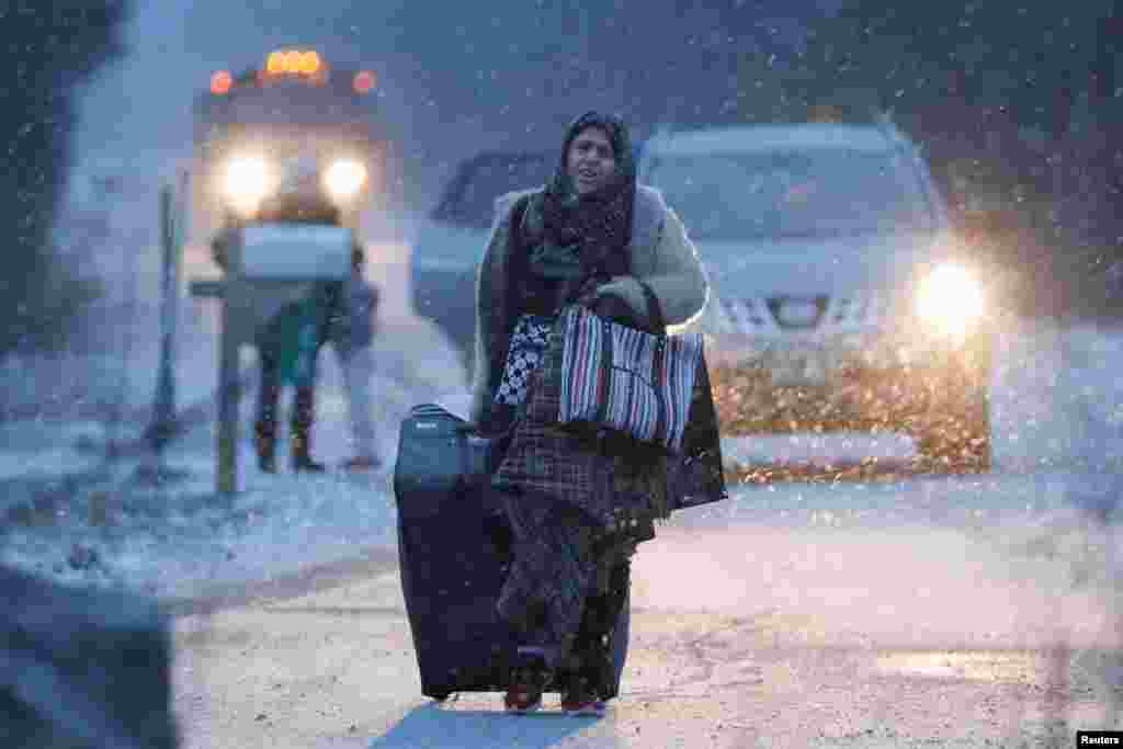 A woman walks toward the border to cross the U.S.-Canada border into Hemmingford, Quebec, Canada, after arriving in a taxi with a group that claimed to be from Syria.