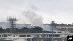 Asap kebakaran mengepul dari gedung yang disebut "18th Wing Hazardous Materials Pharmacy" di Pangkalan Udara Kadena, pulau Okinawa, Jepang, Senin pagi, 22 Juni 2020. (Foto: Kyodo News via AP)