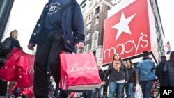 FILE - Shoppers carry bags as they cross a pedestrian walkway near Macy's in Herald Square, in New York. 