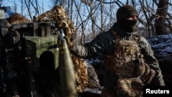 یک سرباز اوکراینی روز چهارشنبه ۱ آذر در منطقه دونتسک یک گلوله توپ را در دست گرفته‌ است